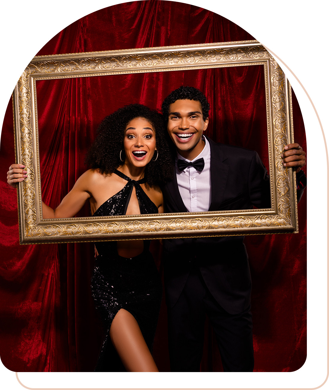 A joyful couple posing with a golden frame against a red velvet backdrop.