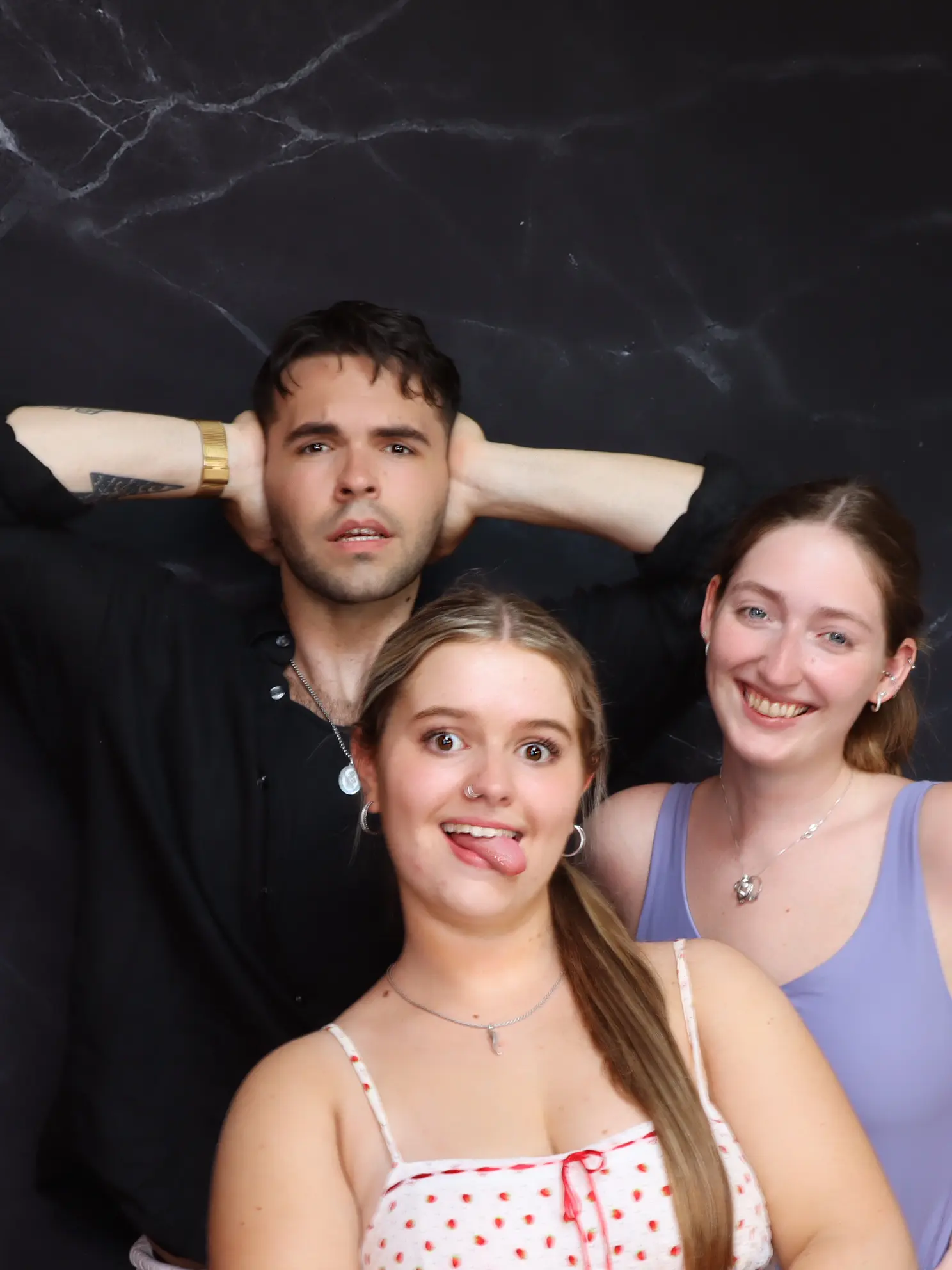 Three friends posing happily against a dark background.