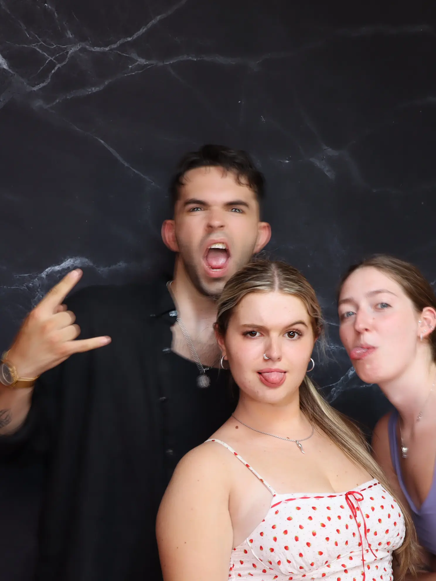 Three young people posing playfully against a dark background.