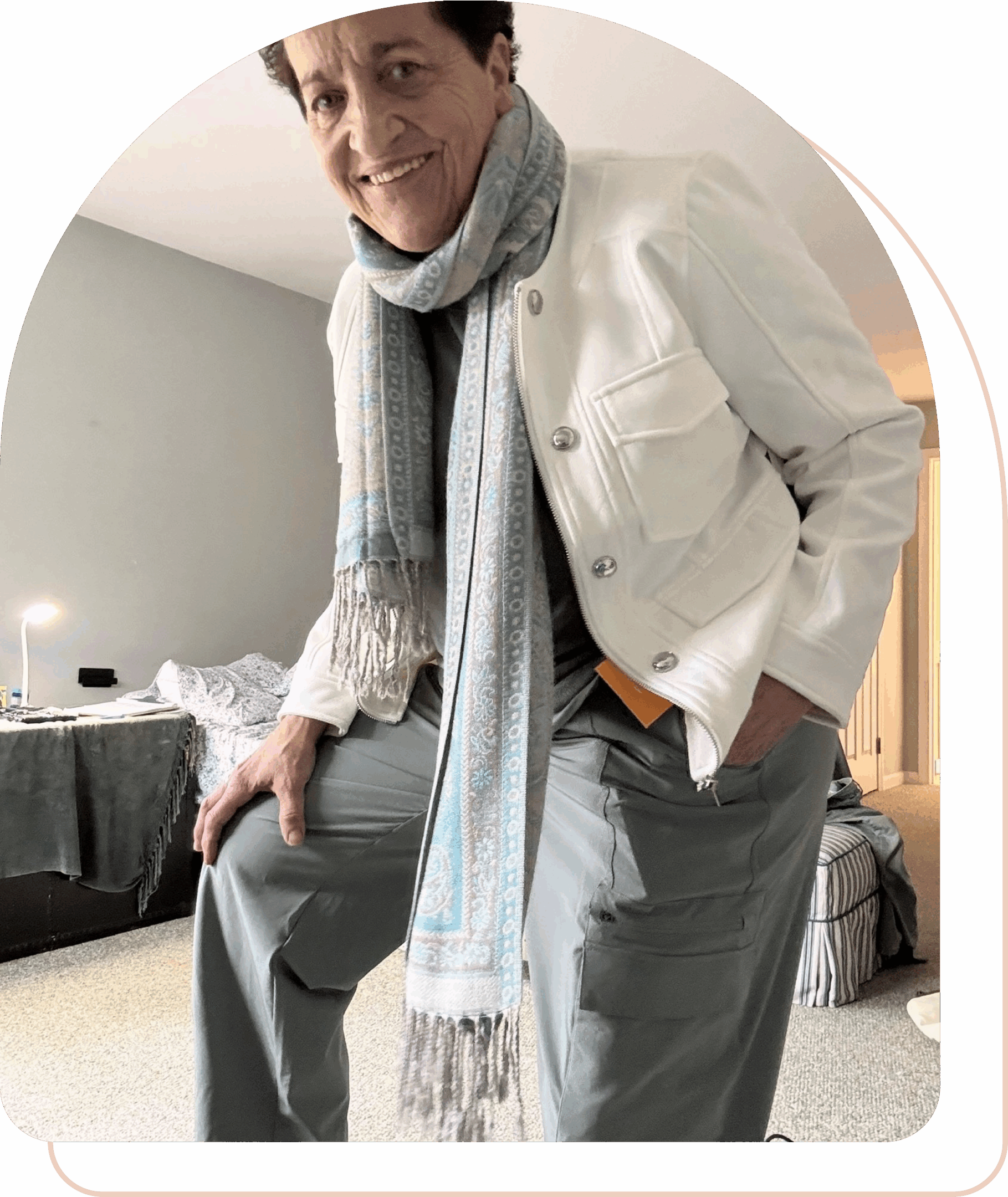 Elderly man dressed stylishly with a long scarf and white jacket.